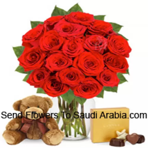 12 roses rouges avec quelques fougères dans un vase en verre accompagnées d'une boîte de chocolats importés et d'un mignon ours en peluche brun de 12 pouces de hauteur