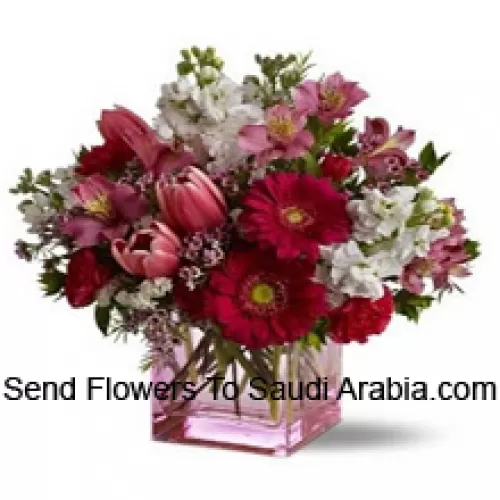 Rosas rojas, tulipanes rojos y flores variadas con rellenos de temporada dispuestas hermosamente en un jarrón de cristal