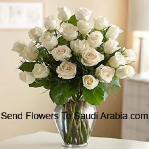 24 roses blanches avec quelques fougères dans un vase en verre