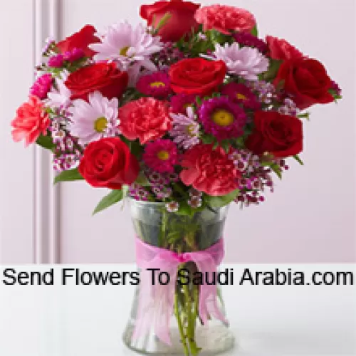 Roses rouges, œillets rouges et autres fleurs assorties disposées magnifiquement dans un vase en verre